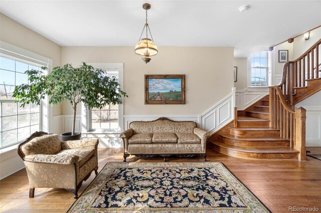 living area with stairs, a decorative wall, and wood finished floors