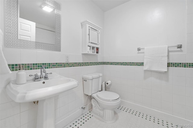 7996 Bradburn Blvd, Westminster, CO 80030 - bathroom featuring tile walls, toilet, and a wainscoted wall