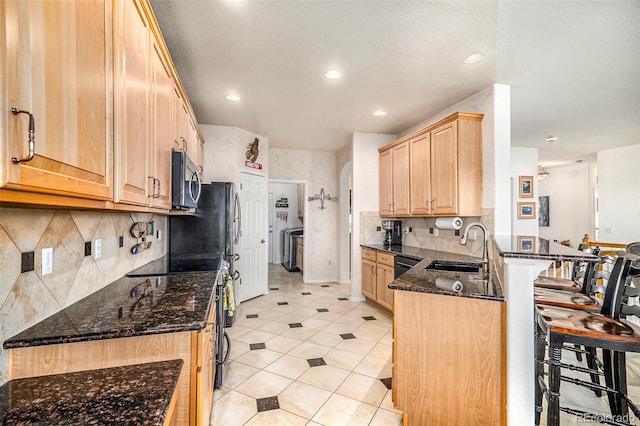 kitchen with kitchen peninsula, sink, a kitchen breakfast bar, electric range, and dark stone countertops