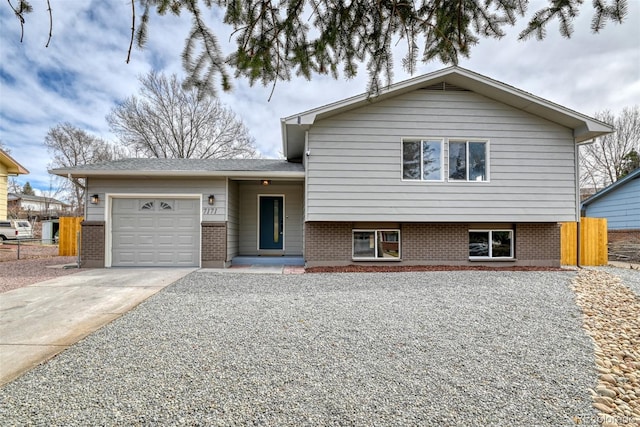 tri-level home with brick siding, concrete driveway, a garage, and fence