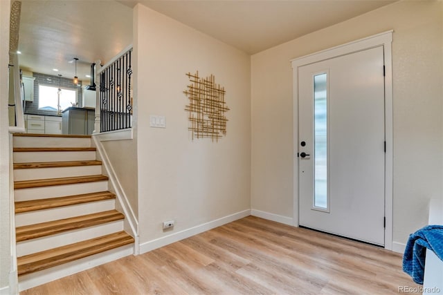 entrance foyer featuring stairway, light wood-style floors, and baseboards