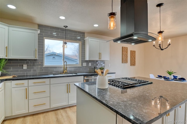 kitchen featuring island range hood, gas stovetop, a sink, light wood-style floors, and a center island