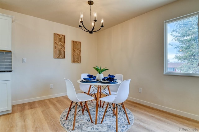 dining area with light wood finished floors, baseboards, and an inviting chandelier