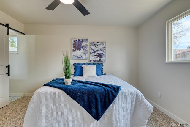 carpeted bedroom featuring a barn door, multiple windows, and baseboards