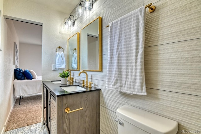 bathroom featuring vanity, ensuite bath, toilet, and a textured wall