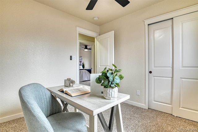 office area featuring ceiling fan, baseboards, and light carpet