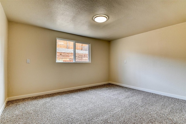 carpeted empty room with baseboards and a textured ceiling