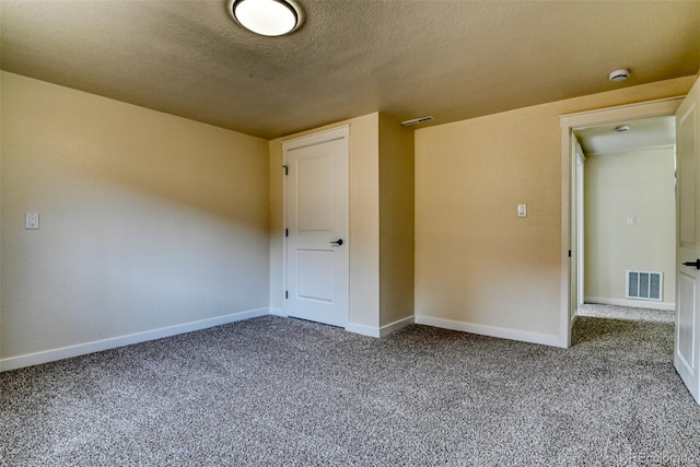 carpeted spare room with visible vents, a textured ceiling, and baseboards