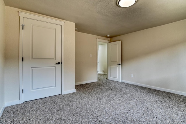 unfurnished bedroom featuring carpet flooring, a textured ceiling, and baseboards