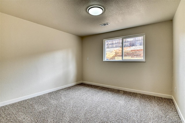 carpeted spare room with visible vents, baseboards, and a textured ceiling