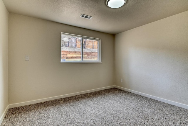 spare room featuring visible vents, a textured ceiling, baseboards, and carpet