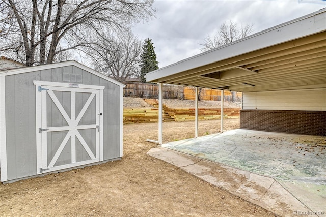 exterior space featuring an outbuilding, a patio, fence, a shed, and a carport