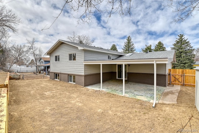 back of house with a patio area, brick siding, a carport, and fence