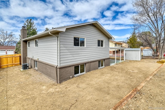 back of house with an outbuilding, cooling unit, fence, and a chimney