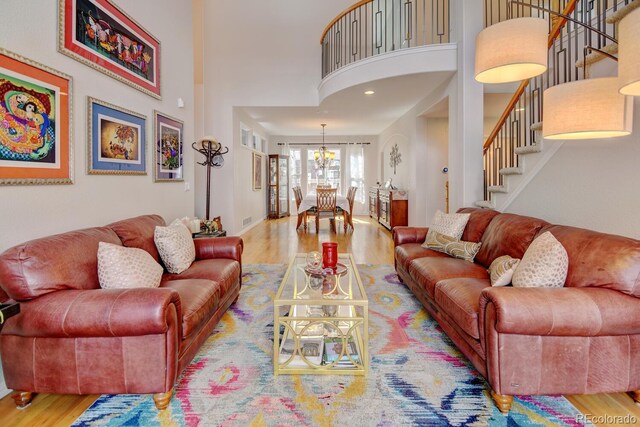 17613 E Peakview Ave, Aurora, CO 80016 - living room featuring stairs, a chandelier, a high ceiling, and wood finished floors
