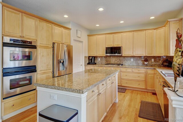 17613 E Peakview Ave, Aurora, CO 80016 - kitchen with light brown cabinetry, a kitchen island, light wood-style floors, tasteful backsplash, and appliances with stainless steel finishes