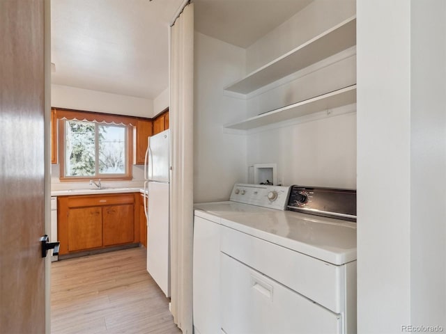 laundry room featuring light hardwood / wood-style flooring, washer and dryer, and sink