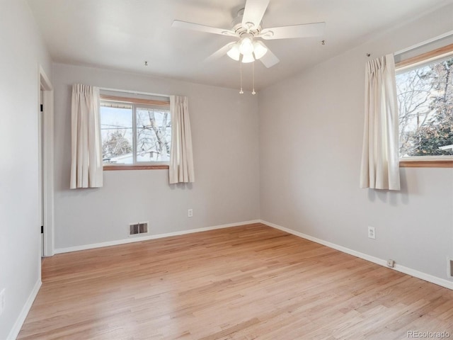 empty room featuring ceiling fan, a healthy amount of sunlight, and light wood-type flooring