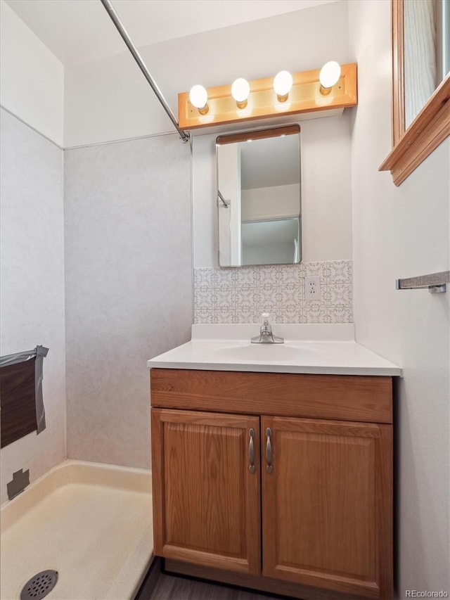 bathroom featuring tasteful backsplash, vanity, and walk in shower