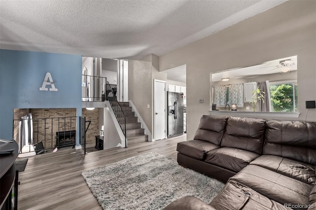 4416 E 93rd Pl, Thornton, CO 80229 - living room with a textured ceiling, wood finished floors, stairs, a ceiling fan, and a fireplace