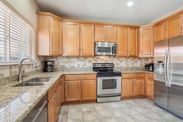 7342 S Mobile St, Aurora, CO 80016 - kitchen featuring appliances with stainless steel finishes, a sink, decorative backsplash, and light stone countertops