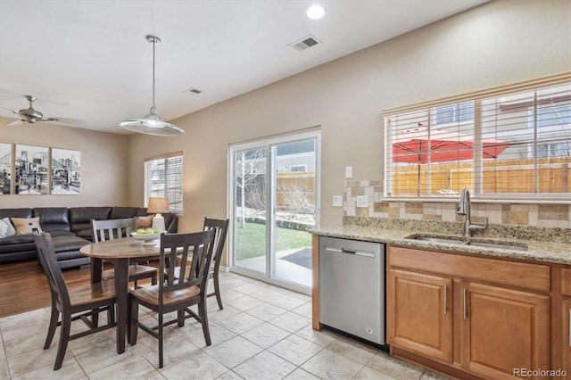 7342 S Mobile St, Aurora, CO 80016 - kitchen with stainless steel dishwasher, a sink, open floor plan, backsplash, and light stone countertops