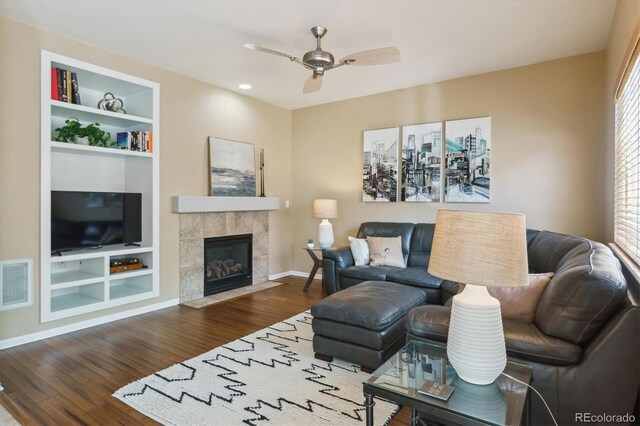 7342 S Mobile St, Aurora, CO 80016 - living area featuring wood finished floors, a ceiling fan, baseboards, built in features, and a tiled fireplace