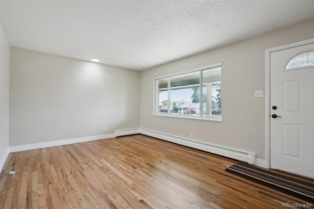 entryway featuring a textured ceiling, light hardwood / wood-style flooring, and a baseboard heating unit