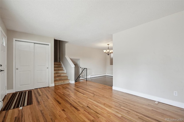 empty room featuring a baseboard radiator, a chandelier, hardwood / wood-style floors, and a textured ceiling