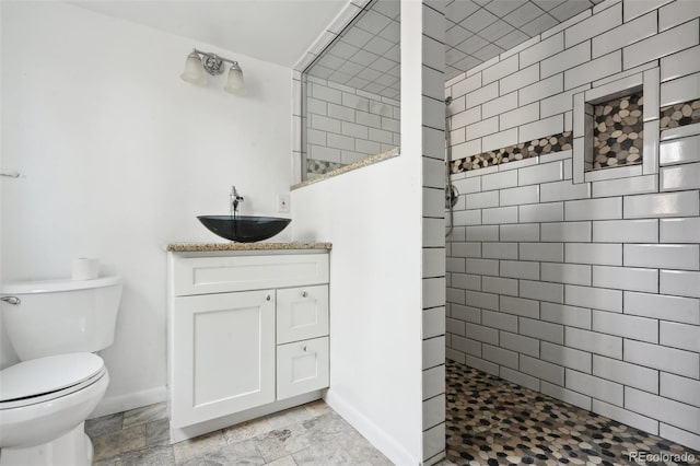 bathroom with vanity, toilet, and a tile shower