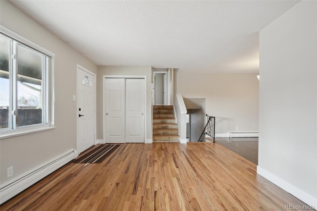 foyer entrance featuring hardwood / wood-style flooring, a baseboard radiator, and a textured ceiling