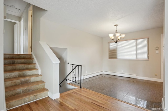 stairway featuring hardwood / wood-style flooring, baseboard heating, a textured ceiling, and a notable chandelier