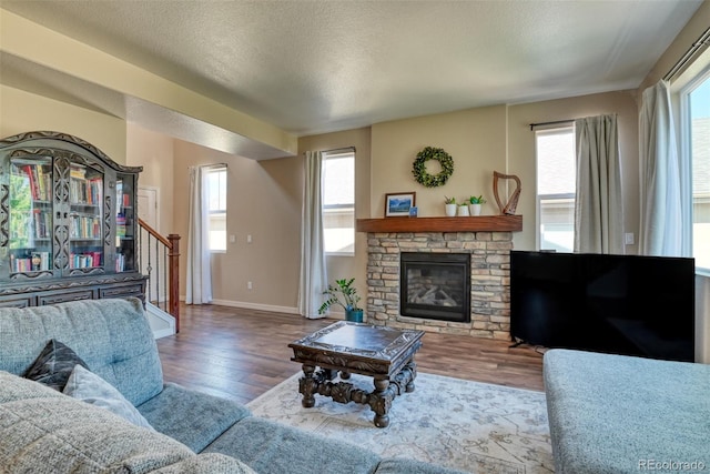 3470 Daydreamer Dr, Colorado Springs, CO 80908 - living room featuring wood finished floors, stairs, healthy amount of natural light, a stone fireplace, and a textured ceiling