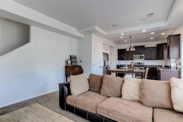 living room featuring light carpet, sink, and a tray ceiling