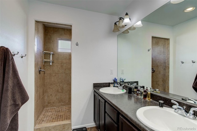 bathroom with a tile shower and vanity