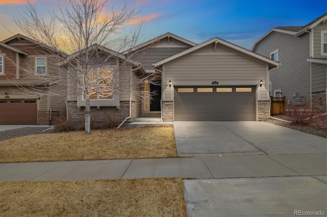 view of front facade with an attached garage, stone siding, and concrete driveway