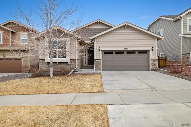 craftsman-style house featuring a garage, driveway, and stone siding