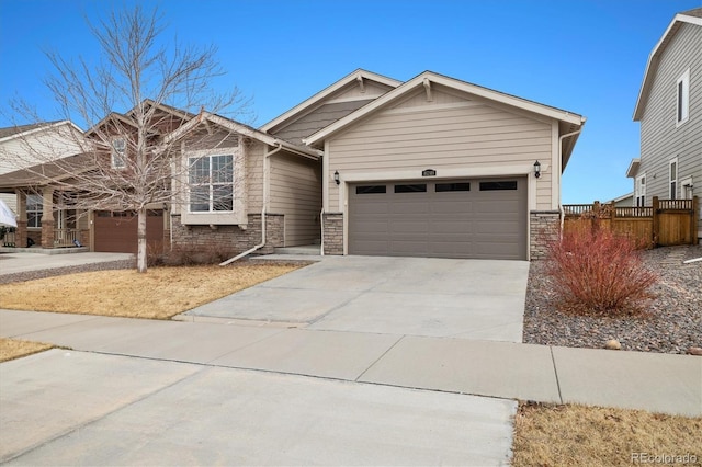 craftsman inspired home featuring a garage, stone siding, fence, and concrete driveway