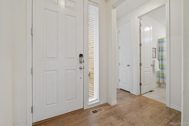 entryway with light wood-type flooring, visible vents, and baseboards