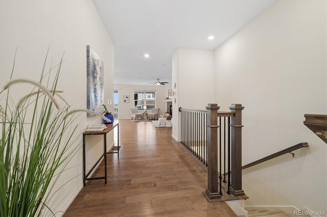 corridor with recessed lighting, baseboards, an upstairs landing, and wood finished floors