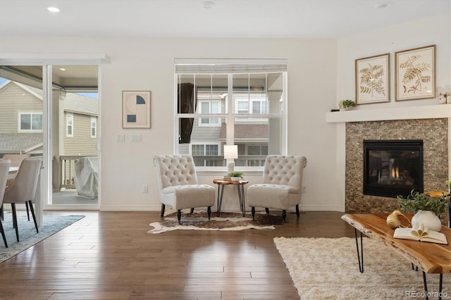 living area with baseboards, dark wood-type flooring, and a healthy amount of sunlight