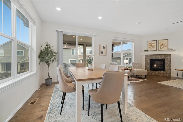 dining room featuring recessed lighting, visible vents, a glass covered fireplace, wood finished floors, and baseboards