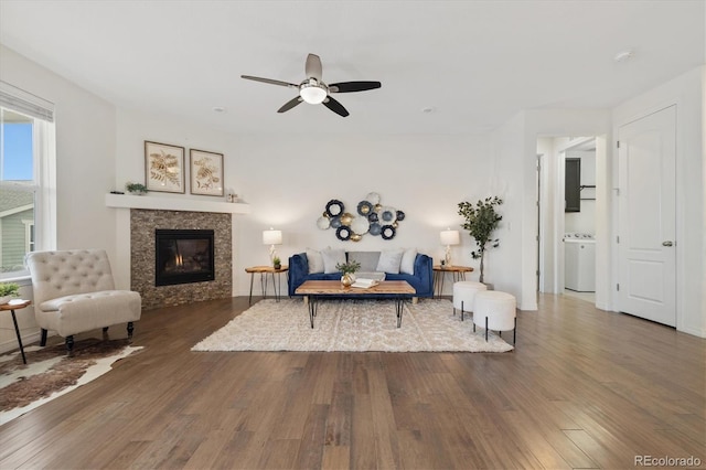 living area featuring ceiling fan, a tiled fireplace, wood finished floors, and washer / dryer