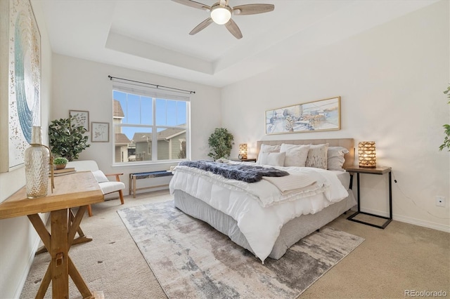 bedroom featuring baseboards, a tray ceiling, ceiling fan, and light colored carpet