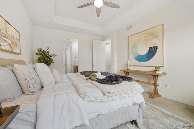 bedroom featuring ceiling fan, carpet floors, visible vents, baseboards, and a tray ceiling