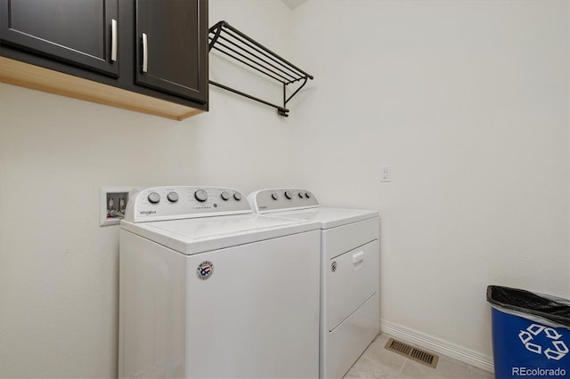 laundry room with light tile patterned floors, separate washer and dryer, visible vents, baseboards, and cabinet space