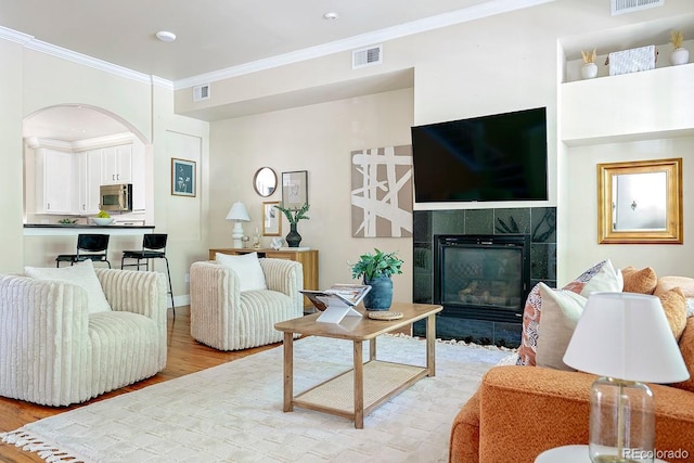 living room featuring crown molding, a fireplace, and light hardwood / wood-style floors