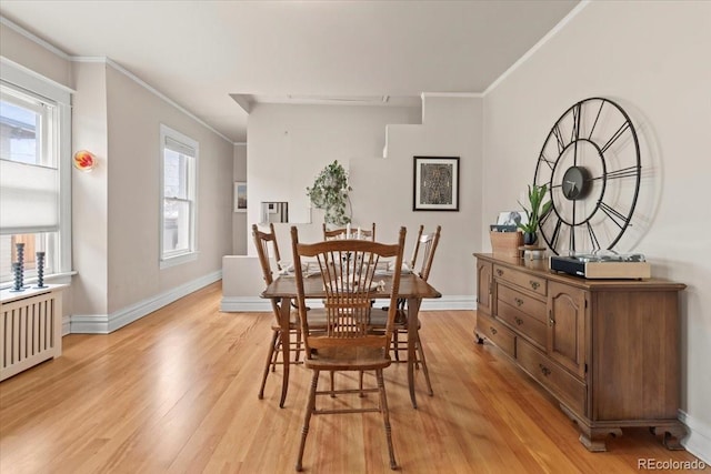 dining room with a healthy amount of sunlight, ornamental molding, radiator, and light wood-type flooring