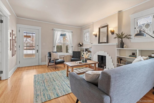 living room featuring a brick fireplace, crown molding, and light wood-type flooring