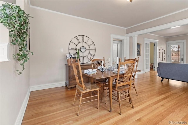 dining room with ornate columns, crown molding, and light hardwood / wood-style flooring